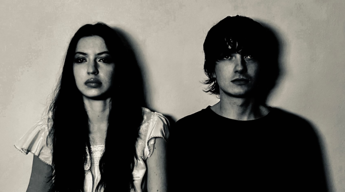 Members of the band Witch Post leaning against a wall in black and white.